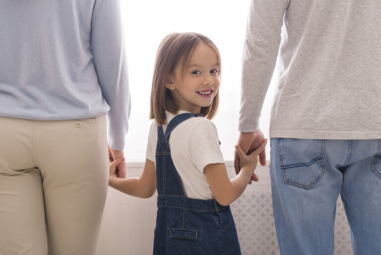 Adoption Concept. Adorable Little Girl Holding Hands With Unrecognizable Man And Woman And Smiling, Bonding With Her Foster Parents, Crop